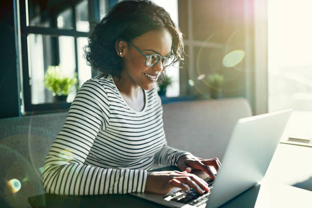 Young African woman smiling and working online with a laptop stock photo