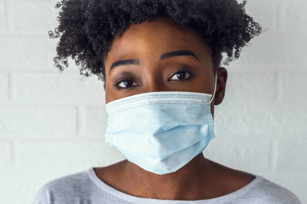 Young African Woman Wearing A Surgical Face Mask Portrait of young African-American woman wearing disposable medical face mask surgical mask stock pictures, royalty-free photos & images