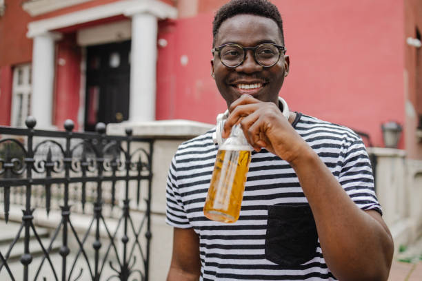 Young African-American man is drinking beer on the street stock photo