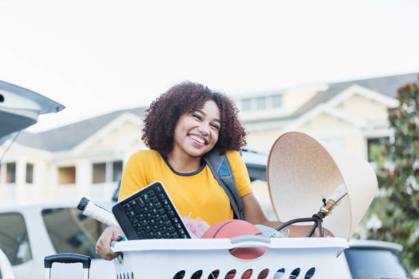 Young African-American woman moving house A young African-American woman moving household belongings. She is unloading her car, moving into a new house, apartment or dorm room. college dorm stock pictures, royalty-free photos & images