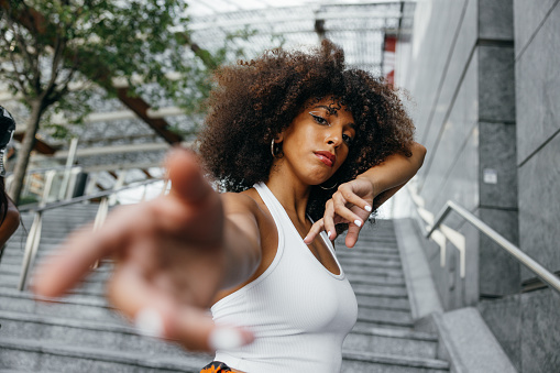 Young alternative woman dressing urban clothes posing in city downtown. She’s part of a group of hip hop dancers performing in the city streets.