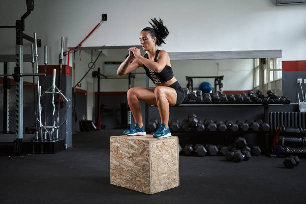 Young and fit woman jumping on a box at the gym stock photo