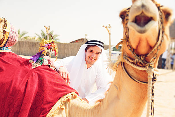 young arabian man with his camels stock photo