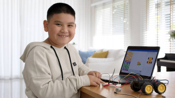 Young asia student remotely learn online at home in coding robot car and electronic board cable in STEM, STEAM, mathematics engineering science technology computer code in robotics for kids concept. stock photo