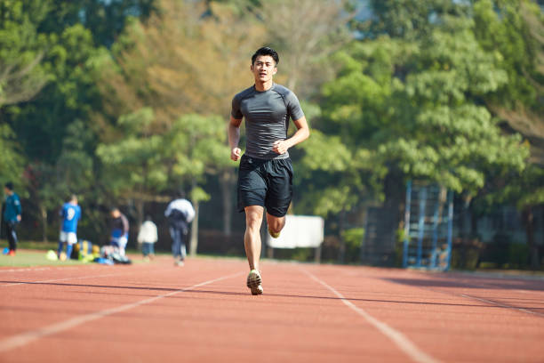 young asian athlete training on running track young asian man male athlete running training exercising on track, rear view. korean culture photos stock pictures, royalty-free photos & images