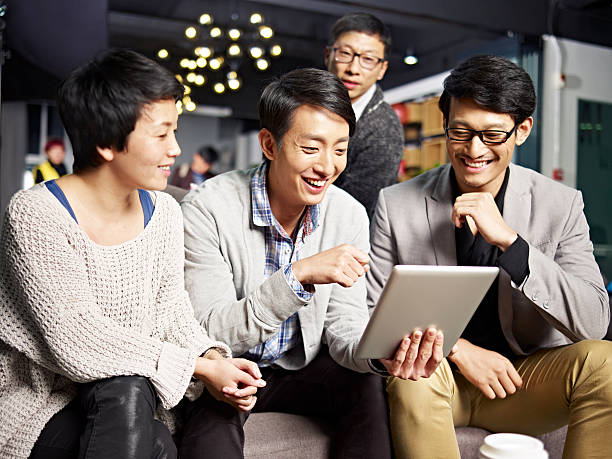 young asian business people using tablet in office young asian businesspeople sitting in sofa looking at tablet computer, happy and smiling. korean culture photos stock pictures, royalty-free photos & images