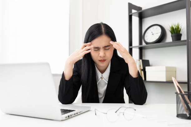 Young asian business woman hand touching head she's feeling depressed stress headache be tired from working with laptop a long time she symptom office syndrome. stock photo