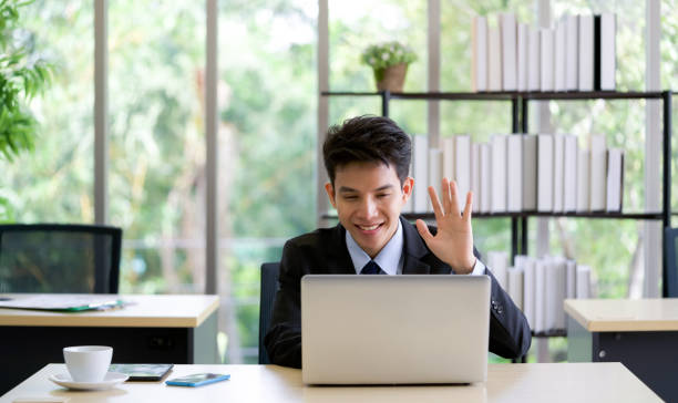 Young asian businessman waved his hand over the wireless communication on the laptop  computer screen. stock photo