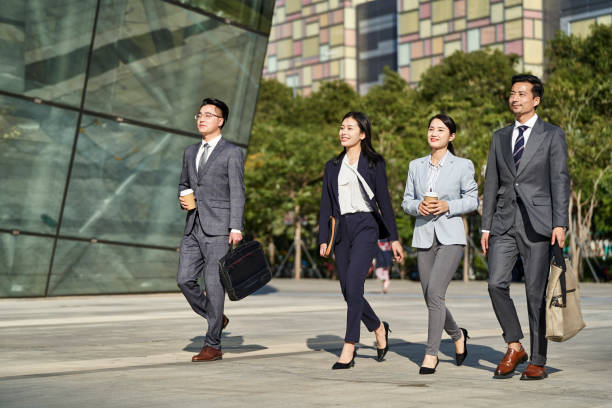 young asian businesspeople walking on street stock photo