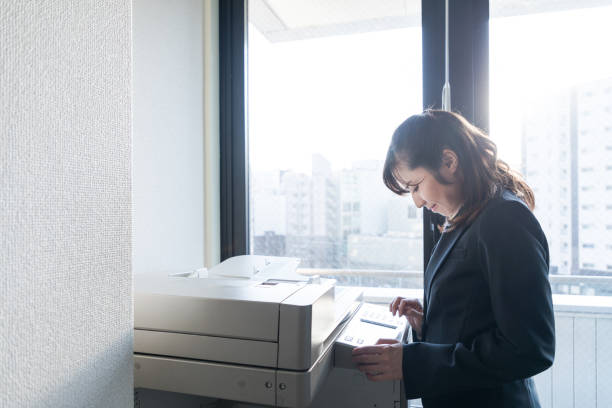 Young asian businesswoman using copying machine. Young asian businesswoman using copying machine. xerox photocopy machine stock pictures, royalty-free photos & images