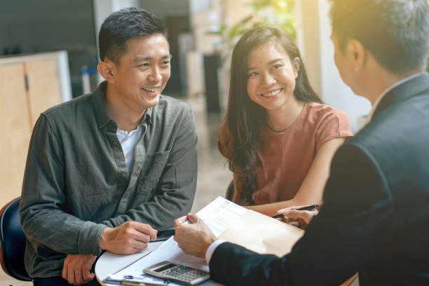 Young asian couple and agent disucss financial planning stock photo