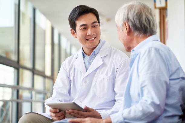 young asian doctor talking to senior patient in hospital stock photo