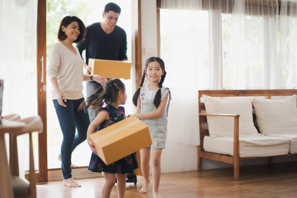 Young Asian family with daughter holds carton and walking in to a new home in moving relocation day which Excited smiling and felling happy. Mother Father and daughter move on a new home concept. Young Asian family with daughter holds carton and walking in to a new home in moving relocation day which Excited smiling and felling happy. Mother Father and daughter move on a new home concept. unpacking stock pictures, royalty-free photos & images
