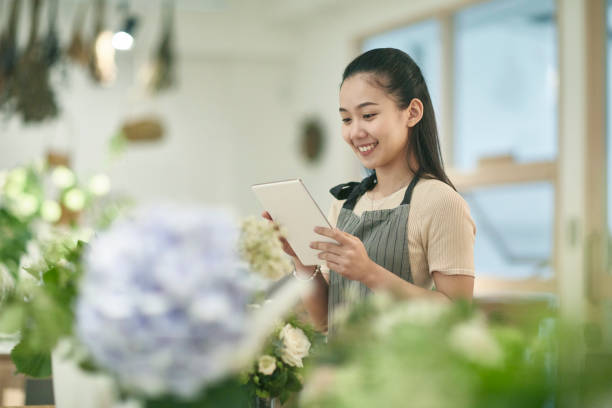 Young Asian Female Florist Using Digital Tablet in the Shop stock photo