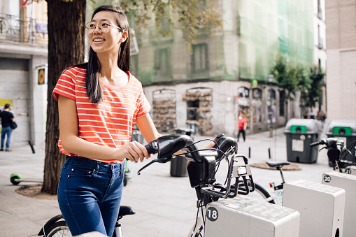 Young Asian woman renting an e-bike to explore Madrid.