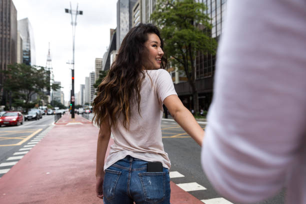 jovem menina asiática chumbo pela mão de seu namorado - siga-me o conceito - avenida paulista - fotografias e filmes do acervo