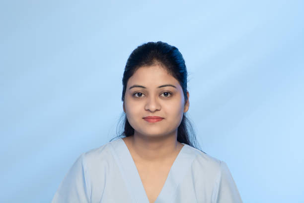 Young Asian Indian Female Lab Technician portrait wearing Sky Blue Uniform in Research Lab Portrait of young Asian Indian Female Lab Technician wearing sky blue uniform, looking straight at the camera, with light cyan colour background. blue red lipstick stock pictures, royalty-free photos & images