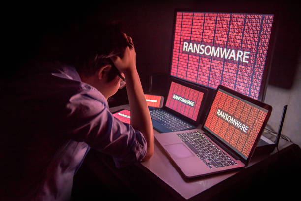Young Asian male frustrated by ransomware cyber attack Young Asian male frustrated, confused and headache by ransomware attack on desktop screen, notebook and smartphone, cyber attack and internet security concepts spyware stock pictures, royalty-free photos & images