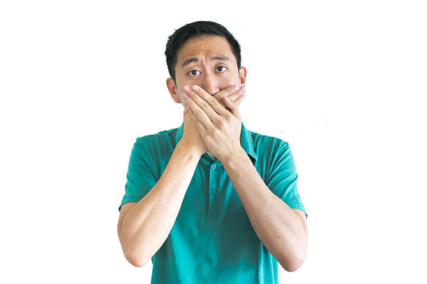 Young Asian man covering his mouth with hands Young Asian man covering his mouth with hands how do you say shut up in japanese stock pictures, royalty-free photos & images