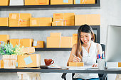 若いアジアの中小企業の所有者の自宅事務所で作業注文にノートを取るします。オンライン マーケティングのパッケージ配信、スタートアップ中小企業起業家やフリーランスの女性の概念
