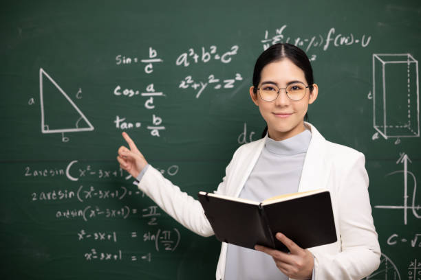 Young asian teacher woman teaching holding book and video conference with student looking camera. Female teacher training the mathematics in classroom blackboard from online course. stock photo
