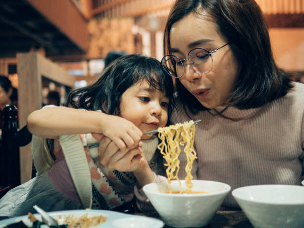 Young asian woman and her daughter enjoying in Korea restaurant. Happy Asian family of mother and daughter playing and laughing while having dinner. korean culture photos stock pictures, royalty-free photos & images