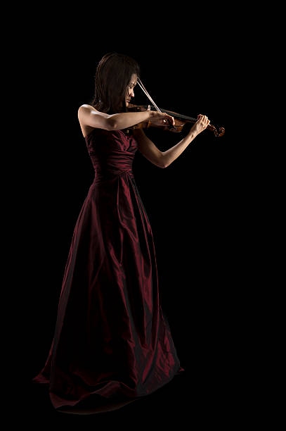 young asian woman playing the violin on black stock photo
