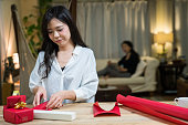 贈り物を包む若いアジアの女性