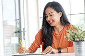 istock Young asian woman wrting on notebook paper on table at home office 1333321961