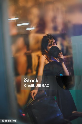 istock Young Asian women wearing black skirts through the window under red-violet neon lights 1345518406