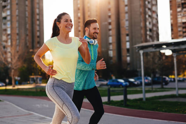 Young attractive couple running outside on sunny day Young attractive and cheerful couple running outside on sunny day jogging stock pictures, royalty-free photos & images