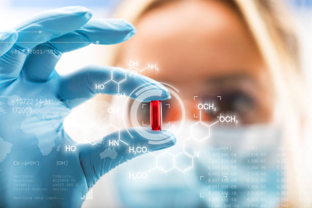 Young attractive female scientist holding a red transparent pill Young attractive female scientist holding a red transparent pill with futuristic scientific air interface with chemical formulas and research data in the foreground laboratory glassware stock pictures, royalty-free photos & images