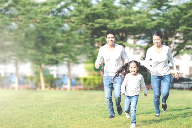 Young attractive happy asian family playing by running together in outside nature park in home school learning or montessori concept with white and blue casual wearing. Asian lifestyle parenting. Young attractive happy asian family playing by running together in outside nature park in home school learning or montessori concept with white and blue casual wearing. Asian lifestyle parenting. Live Insurance stock pictures, royalty-free photos & images