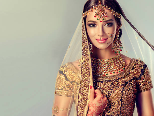 Young attractive model dressed in posh, gildet, indian costume and Kundan style jewelry. Young attractive model dressed in posh, gildet, indian costume, Kundan style jewelry and henna tattoo(mehndi) on the hands. Traditional Indian costume lehenga choli. Fascination of classic national indian style. indian jewelry stock pictures, royalty-free photos & images