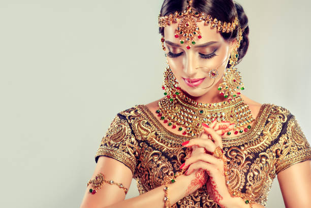 Young attractive model dressed in posh, gildet, indian costume and Kundan style jewelry. Young attractive model dressed in posh, gildet, indian costume, Kundan style jewelry and henna tattoo(mehndi) on the hands. Traditional Indian costume lehenga choli. Fascination of classic national indian style. indian jewelry stock pictures, royalty-free photos & images