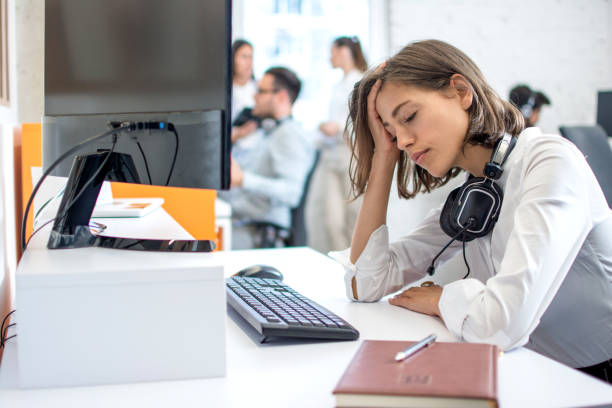 Young attractive woman operator with headset over neck suffering from headache stock photo