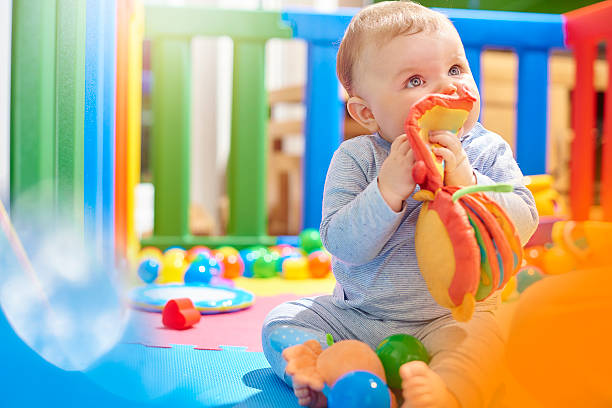 Young baby boy playing with his toys in playpen  playpen stock pictures, royalty-free photos & images