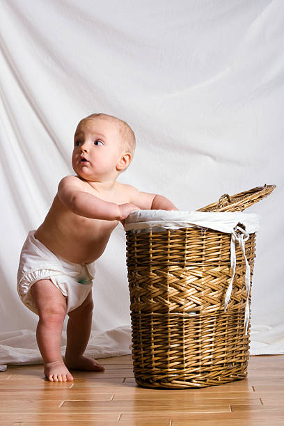 Young baby looking in a laundry basket feeling guilty stock photo