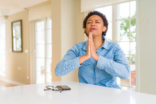 Young beautiful african american woman begging and praying with hands together with hope expression on face very emotional and worried. Asking for forgiveness. Religion concept.  prayer request stock pictures, royalty-free photos & images
