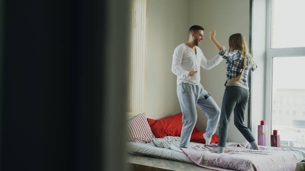 Young beautiful and loving couple dancing rocknroll dance on bed in the morning at home stock photo