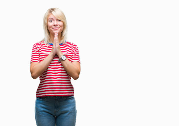 Young beautiful blonde woman over isolated background praying with hands together asking for forgiveness smiling confident.  prayer request stock pictures, royalty-free photos & images