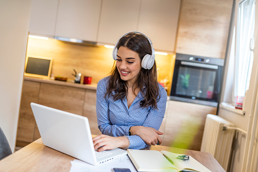 Businesswoman with headphones sitting at desk during the break. Casual businesswoman arm on desk rest pose with laptop computer and listening music via headphone, work at home with relax feeling concept.