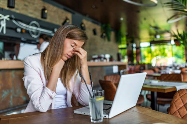 Young beautiful businesswoman tired from work. Young and beautiful businesswoman tired from work at coffee shop. Woman holding her head. Business women stressed and under pressure. Young beautiful businesswoman tired from work. struggle stock pictures, royalty-free photos & images