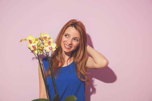 Young beautiful cute girl posing with orchid flowers. stock photo