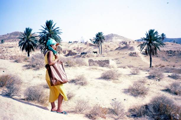 Young beautiful girl in the middle of Sahara desert A picture of a young beautiful girl near a oasis in the middle of Sahara desert. Vintage photo. Tunisia. 1980 tunisia woman stock pictures, royalty-free photos & images