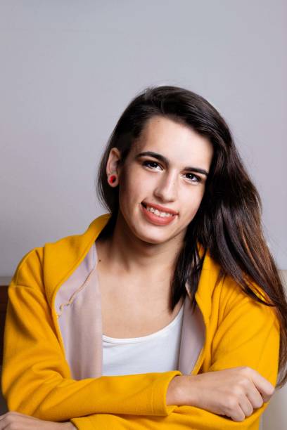 Young beautiful hispanic transgender woman against grey background stock photo