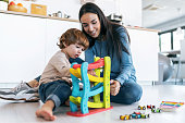 istock Young beautiful mother playing on the floor with her son in living room at home. 1352644618