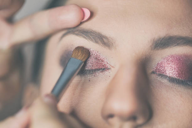 Young beautiful woman applying make-up by make-up artist. Process of making makeup. stock photo