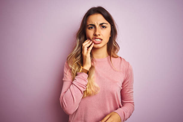 ung vacker kvinna klädd i en tröja över rosa isolerad bakgrund röra munnen med hand med smärtsamma uttryck på grund av tandvärk eller tandsjukdom på tänderna. tandläkar konceptet. - toothache woman bildbanksfoton och bilder