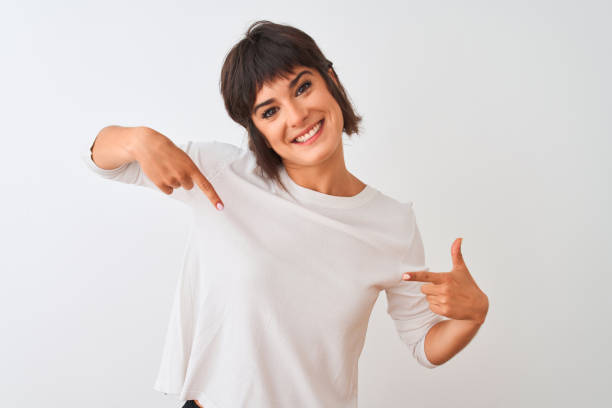 Young beautiful woman wearing casual t-shirt standing over isolated white background looking confident with smile on face, pointing oneself with fingers proud and happy. Young beautiful woman wearing casual t-shirt standing over isolated white background looking confident with smile on face, pointing oneself with fingers proud and happy. white t shirt stock pictures, royalty-free photos & images